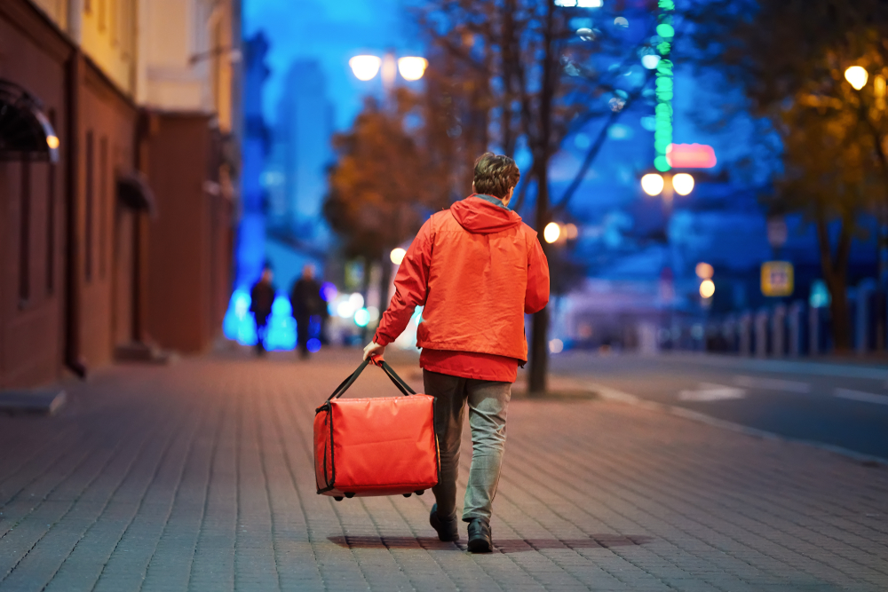 Young Deliveryboy Walking With Red Thermal Bag On Night City